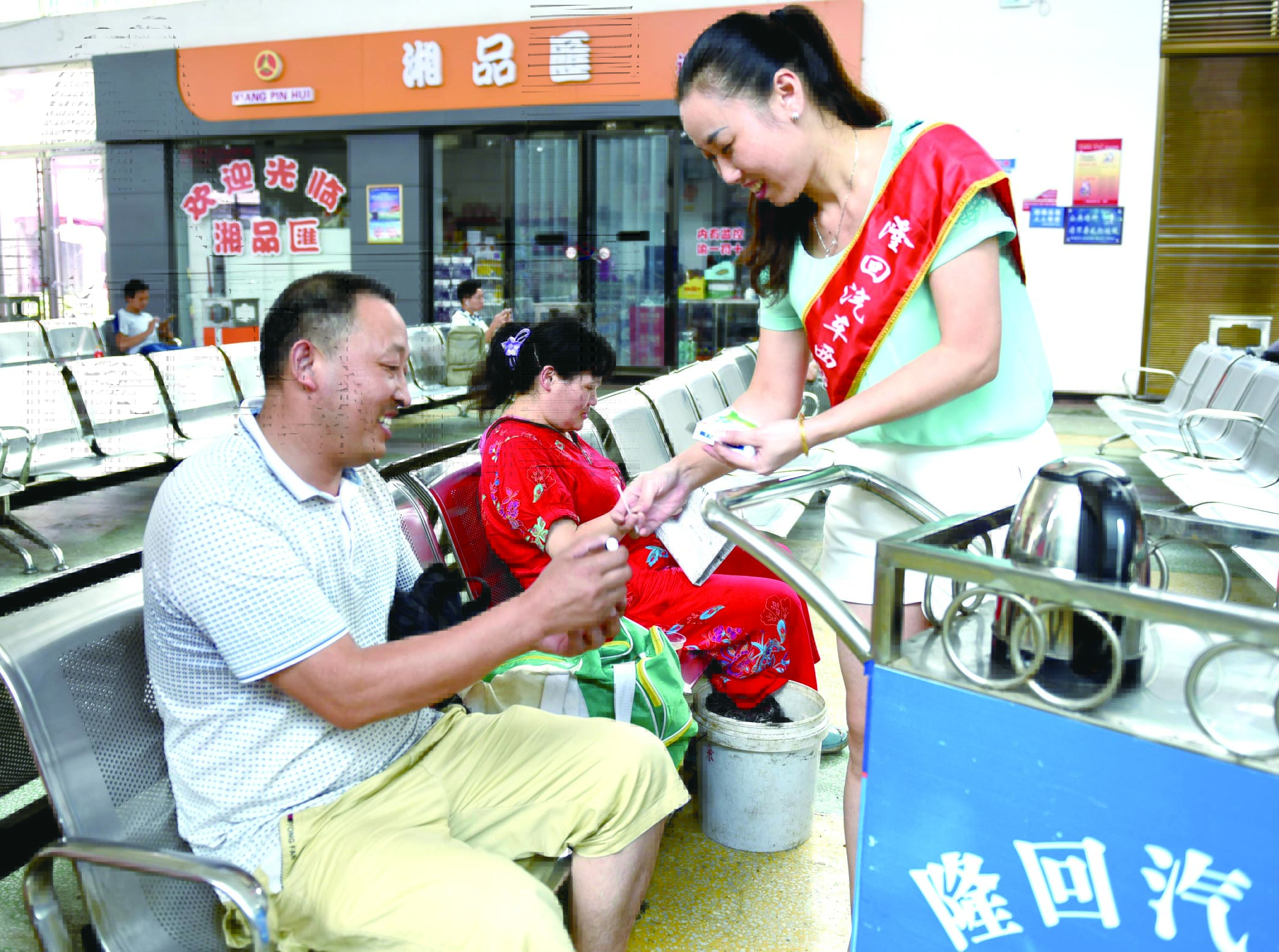 隆回分公司汽車西站工作人員正在為旅客免費贈送藿香正氣水。